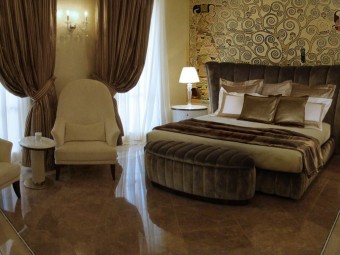 CAMERA PADRONALE. Pavimento in marmo con intarsi decorativi. Rivestimento realizzato con stucco Gold (SIKKENS). Parete centrale decorata con affresco esclusivo. Letto, pouf, comodini e poltrone rivestite in velluto (MINOTTI COLLEZIONI). Tavolino in marmo con base in ottone satinato (MINOTTI COLLEZIONI).