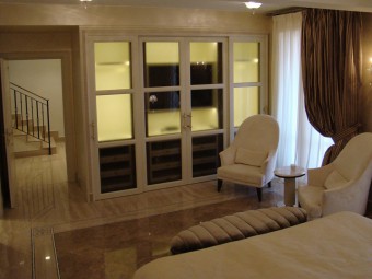 CAMERA PADRONALE. Arredamento personalizzato con zona TV ed illuminazione integrata con sensore a movimento (BEZUS - LPL). Poltrone rivestite in velluto (MINOTTI COLLEZIONI). Tavolino in marmo con base in ottone satinato (MINOTTI COLLEZIONI).