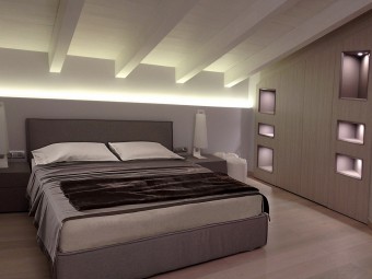 CAMERA FIGLIO GRANDE. Soffitto con travi a vista. Pavimento in parquet Spazzolato Rovere Argento. Piccola cabina armadio con nicchie illuminate (BEZUS - LPL). Letto imbottito con rivestimento in tessuto (DOIMO). Comodini in legno laccato (DOIMO).