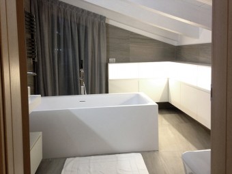 BAGNO PADRONALE. Soffitto con travi a vista. Pavimento e rivestimento in gres porcellanato. Arredamento personalizzato con illuminazione incorporata (BEZUS - LPL).